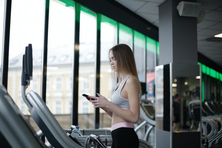 Slim young lady training on treadmill in modern gym